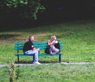 Auf einer Parkbank sitzen 2 Personen und schauen sich an.